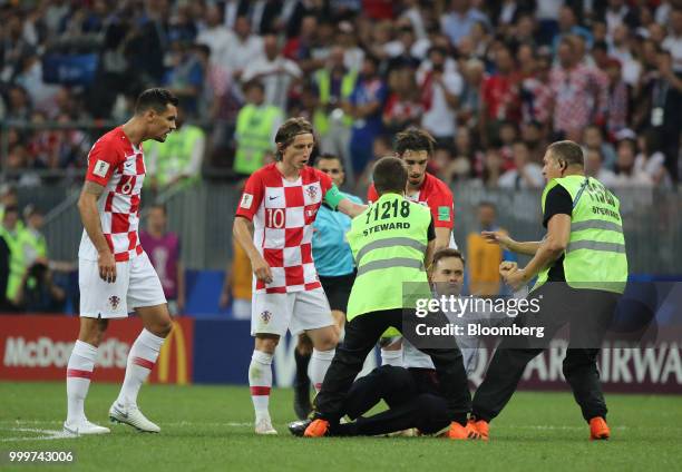 Players from the Croatia team stand as security guards remove a protester from the pitch during the FIFA World Cup final match in Moscow, Russia, on...