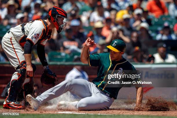 Matt Olson of the Oakland Athletics slides into home plate to score a run past Buster Posey of the San Francisco Giants during the fourth inning at...