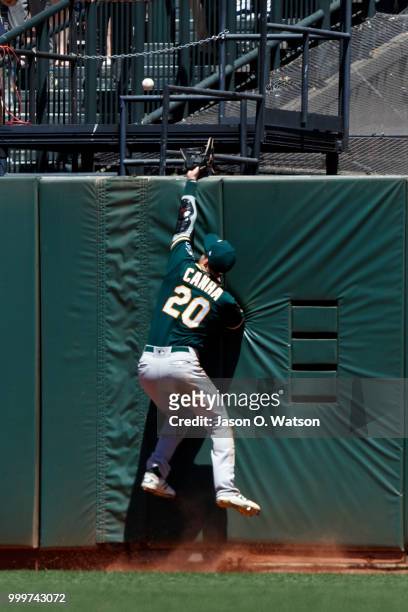 Mark Canha of the Oakland Athletics leaps for but is unable to hit a fly ball hit for a home run by Chase d'Arnaud of the San Francisco Giants during...