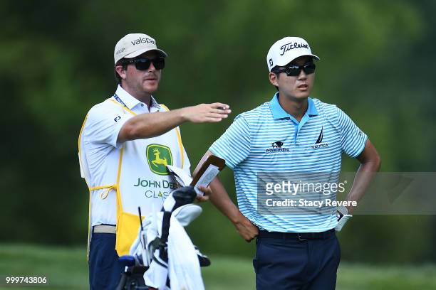 Michael Kim speaks with his caddie Andrew Gunderson on the 15th hole during the final round of the John Deere Classic at TPC Deere Run on July 15,...
