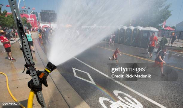 Firehouse spits out a mist for spectators to get wet in and try to keep cool. Scott Dixon, of New Zealand, takes the checkered flag at Honda Indy...