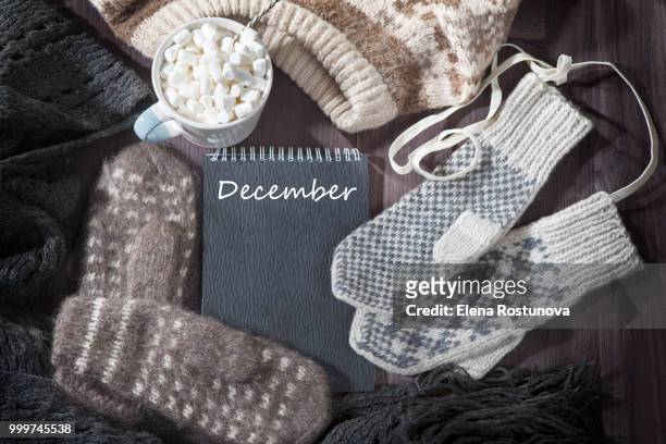 the woolen mittens, scarf and sweater with a black notepad for notes lie on the table. copy space. - the mittens stockfoto's en -beelden