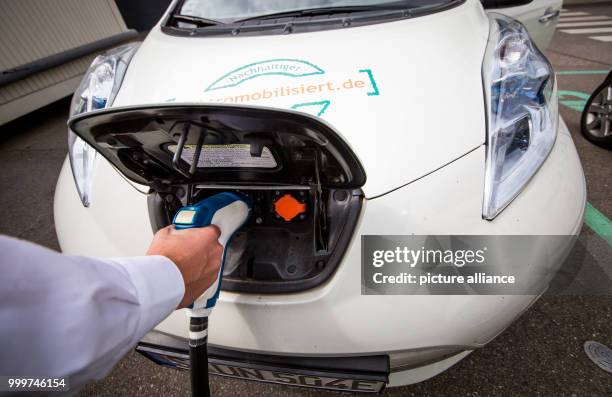 Man loads an e-car outside the Fraunhofer Institute for Industrial Engineering in Stuttgart, Germany, 4 September 2017. Photo: Christoph Schmidt/dpa