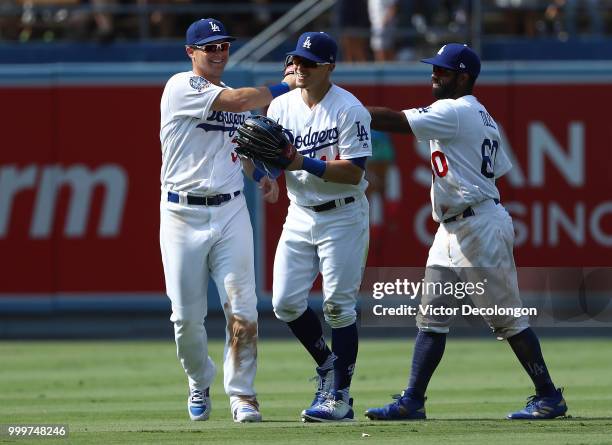 Joc Pederson, Enrique Hernandez and Andrew Toles of the Los Angeles Dodgers celebrate in the outfield after the last out against the Los Angeles...