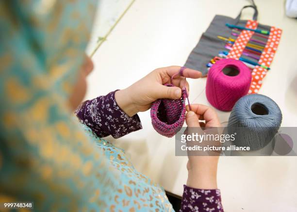 Refugee woman from Afghanistan participates in a sewing course organised by Kati Hyyppaei from Finalnd in the room of a refugee home in Berlin,...