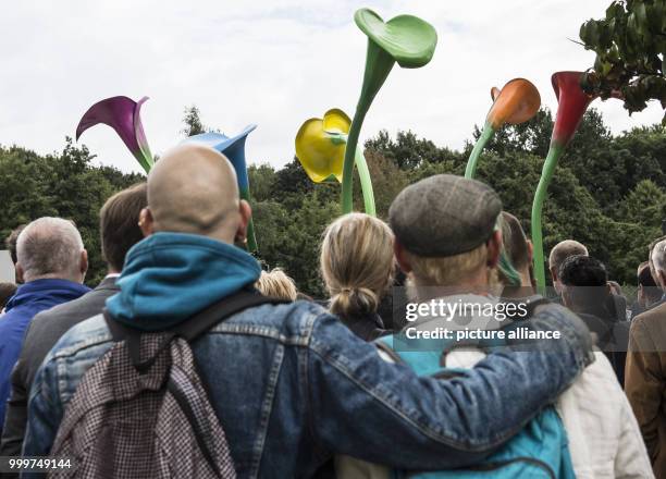 People participate in the inauguration of the monument made up of giant colourful calla lilies at the Magnus-Hirschfeld-Ufer in Berlin, Germany, 7...