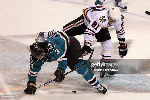 Douglas Murray of the San Jose Sharks moves the puck as he is checked from behind by Marian Hossa of the Chicago Blackhawks in Game Two of the...