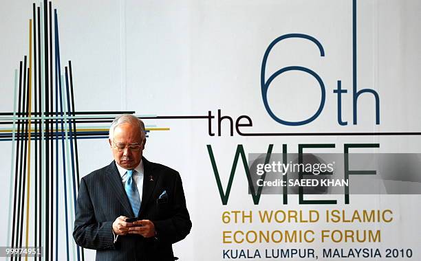 Malaysia Prime Minister Najib Razak checks his mobile phone while waiting to receive state leaders for the opening ceremony of the 6th World Islamic...