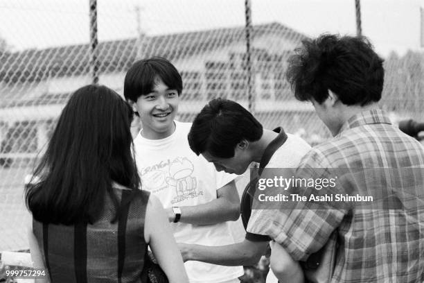 Prince Fumihito talks with friends while playing tennis on August 7, 1986 in Karuizawa, Nagano, Japan.