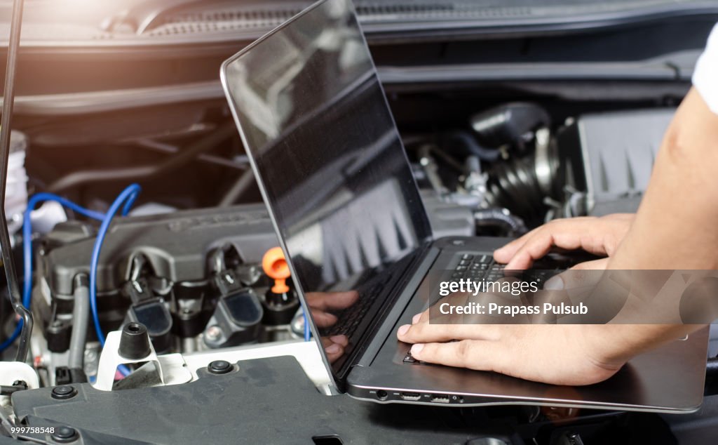 Detail of a mechanic using electrnoic diagnostic equipment to tune a car