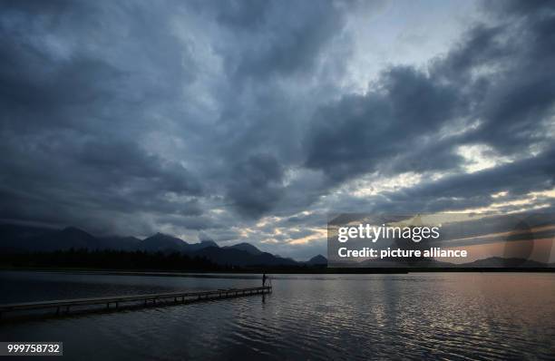 Woman fishes on a footbridge at Hopfensee lake at sundown, near Fuessen, Germany, 7 September 2017. Photo: Karl-Josef Hildenbrand/dpa