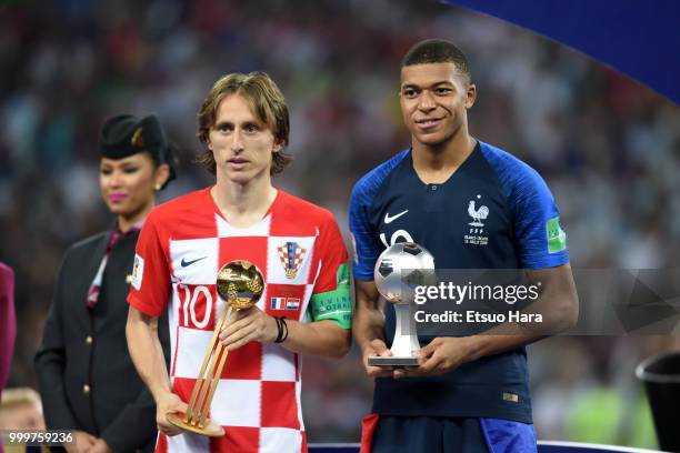 Luka Modric of Croatia with the FIFA Golden Ball trophy and Kylian Mbappe of France with the silver ball trophy pose for photographers after the 2018...