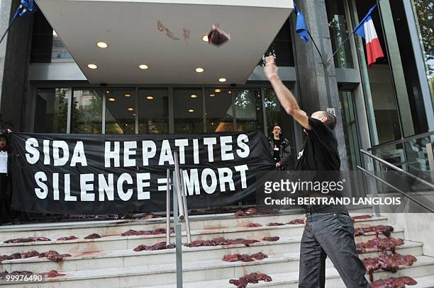 An activist of French branch of Act Up throws an animal liver during a demonstration in front of the Health ministry on May 19, 2010 in Paris, after...