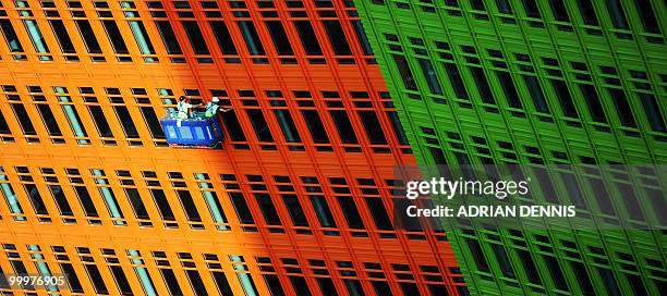 Window cleaners standing in a cradle work on a new building in central London on May 18, 2010. AFP PHOTO / Adrian Dennis