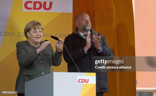 German chancellor Angela Merkel and the minister of economy Harry Glawe stand on stage together at the market place in Barth, Germany, 8 September...