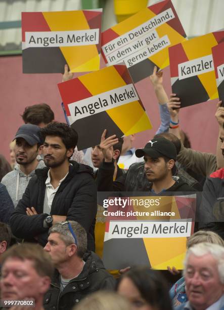 Supporters hold up posters during a CDU election campaign event in Wolgast, Germany, 08 September 2017. Photo: Stefan Sauer/dpa