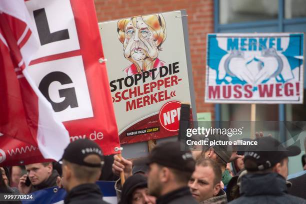 Protesters hold up a posters that read "Stop human trafficker Merkel", to the right "Merkel must go!" during a CDU election campaign event in...