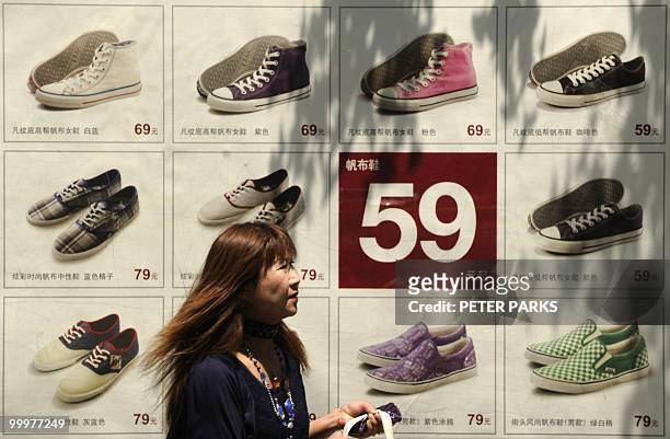Woman passes a poster advertising cut-price shoes on a street in Beijing on May 19, 2010. The Chinese premier said recently that the global financial...