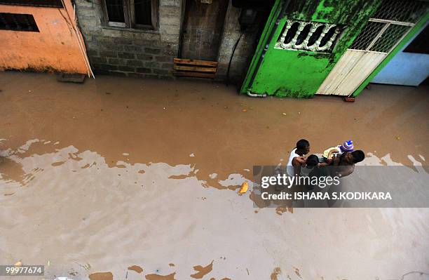 Sri Lankan men walk down a flooded road in Colombo on May 18, 2010. Heavy rains forced the indefinite postponement of Sri Lanka's military parade...