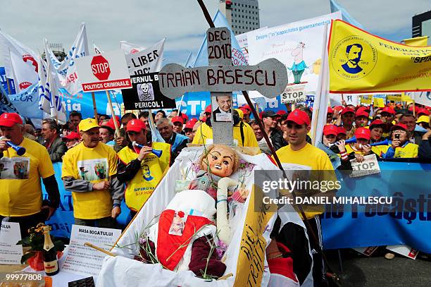 Romanian Trade Union members shout anti-governmental slogans as they dispay a satirical coffin containing an effigy representing Romanian President...