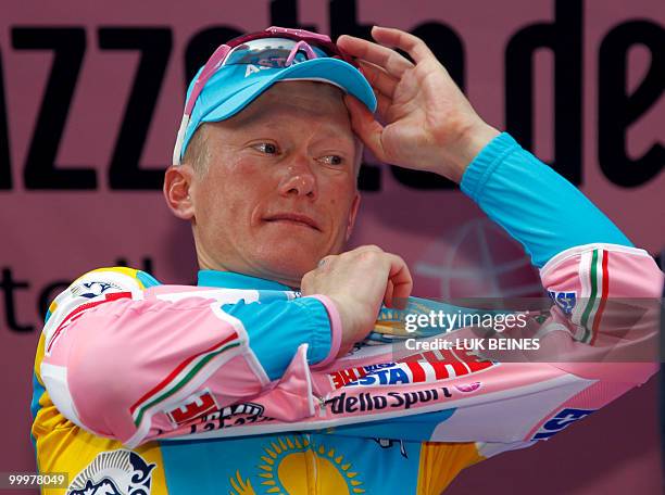 Kazakhstan's Alexandre Vinokourov puts on the pink jersey of leader as he celebrates on the podium of the tenth stage of the 93rd Giro d'Italia going...