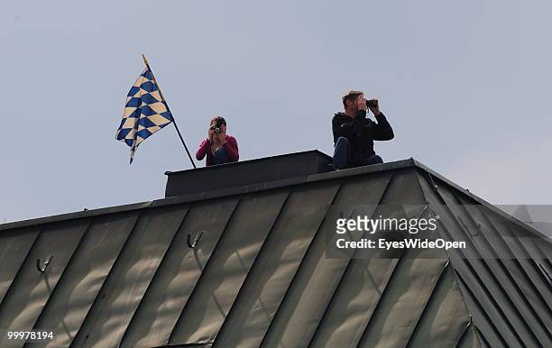 People with the Bavarian flag sitting on a roof overlooking the famous Marienplatz. On May 09, 2010 in Munich, Germany.