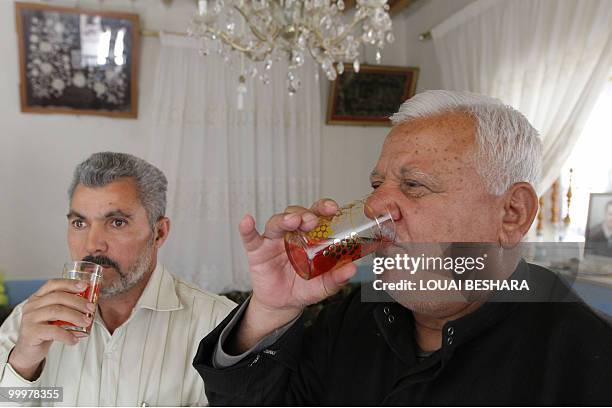 Syrian villagers drink are offered a traditional rose syrup drink at a house in the Syrian village of al-Mrah, 60 kms north of the capital Damascus,...