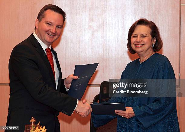 Chris Bowen, Australia's financial services minister, left, shakes hands with Zeti Akhtar Aziz, governor of Bank Negara Malaysia, during the signing...