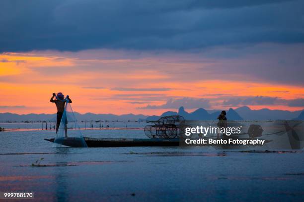 fisherman throw his net to catch to fish on the boat in twilight time - province de songkhla photos et images de collection