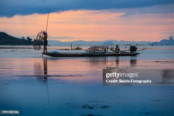 fisherman throw his net to catch to fish on the boat in twilight time - province de songkhla photos et images de collection