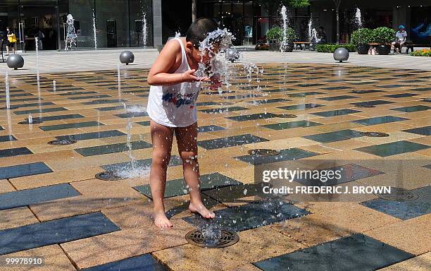 Child cools off at a water fountain at a shopping mall in Beijing on May 19, 2010. China's rising economic prowess means higher living standards for...