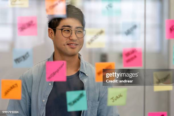 asiatischer mann bei einer kreativen brainstorming - portrait of pensive young businessman wearing glasses stock-fotos und bilder