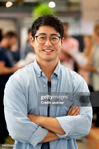 hombre asiático en una oficina creativa con un grupo al fondo - andresr fotografías e imágenes de stock