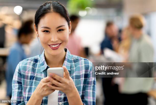 femme d’affaires asiatiques à l’aide de app sur son téléphone cellulaire au bureau - ���������������������������������������������������������������app���������zg357cc��������������������������������������������������������������� photos et images de collection