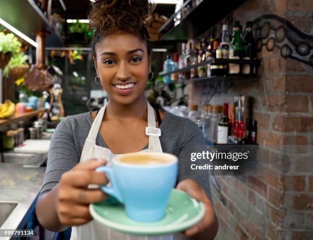 happy waitress serving a cup of coffee at a cafe - andresr stock pictures, royalty-free photos & images