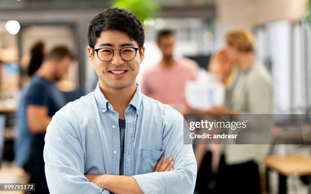 asian man at a creative office with a group at the background - andresr stock pictures, royalty-free photos & images