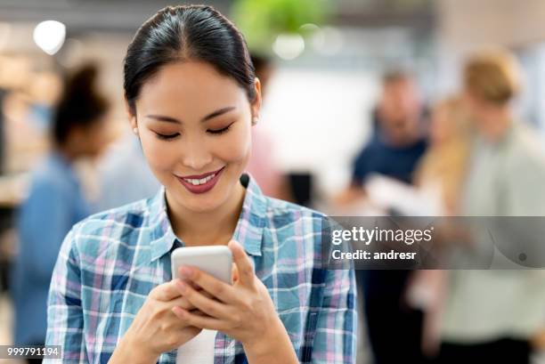 asian business woman using app on her cell phone at the office - andresr stock pictures, royalty-free photos & images