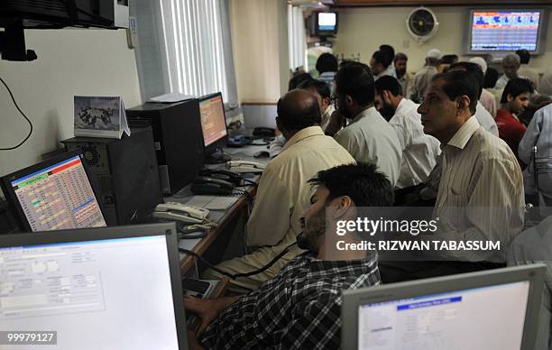 Pakistani stock dealers work at a brokerage house during a trading session in Karachi on May 19, 2010. The benchmark Karachi Stock Exchange 100-index...
