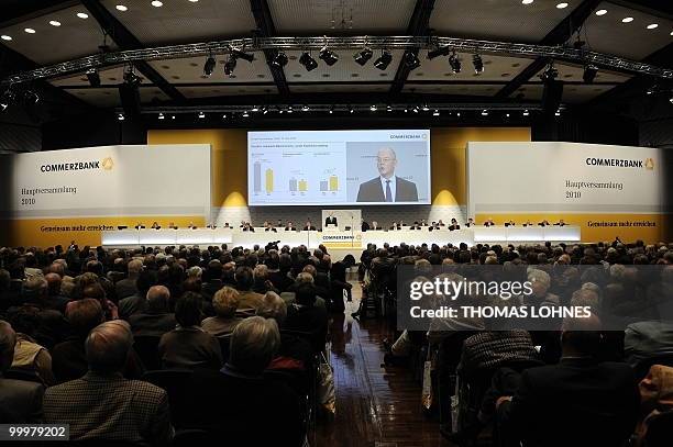 Martin Blessing, chairman of Germany's second biggest bank Commerzbank, is displayed on a giant screen as he speaks to the shareholders during the...