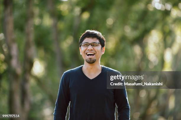 portrait of an asian men who put on glasses at the park - masafumi nakanishi imagens e fotografias de stock