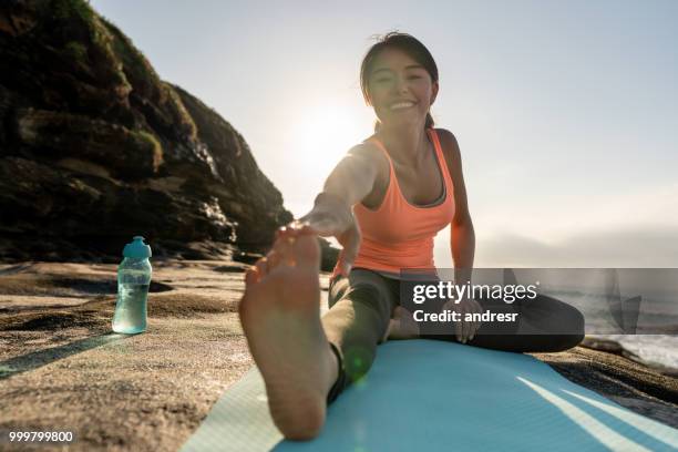 mujer haciendo yoga ejercicios al aire libre junto al mar - andresr fotografías e imágenes de stock