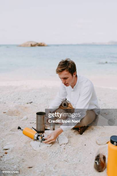 man making coffee on tropical beach in morning while camping, okinawa, japan - okinawa islands stock pictures, royalty-free photos & images