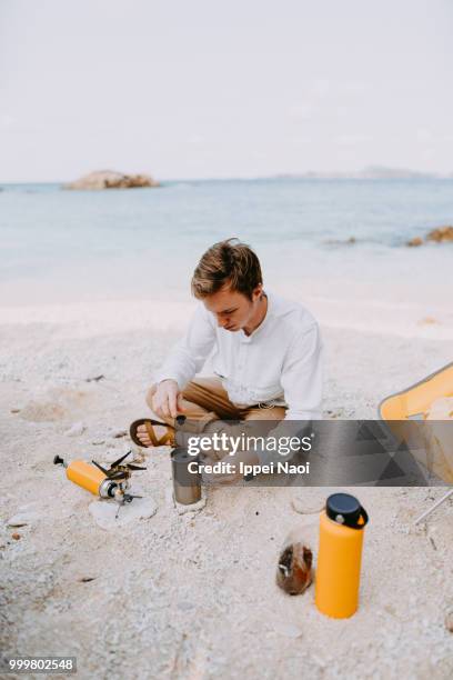 man making coffee on tropical beach in morning while camping, okinawa, japan - okinawa islands stock pictures, royalty-free photos & images