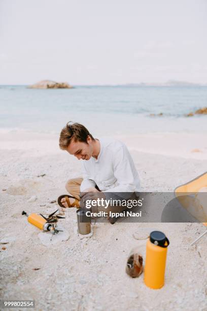 man enjoying making coffee on tropical beach in morning while camping, okinawa, japan - okinawa islands stock pictures, royalty-free photos & images
