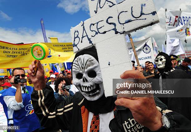 Romanian protester holds a cross reading in Romanian "Down with Basescu" as others shouts anti-governmental slogans during a massive protest in the...