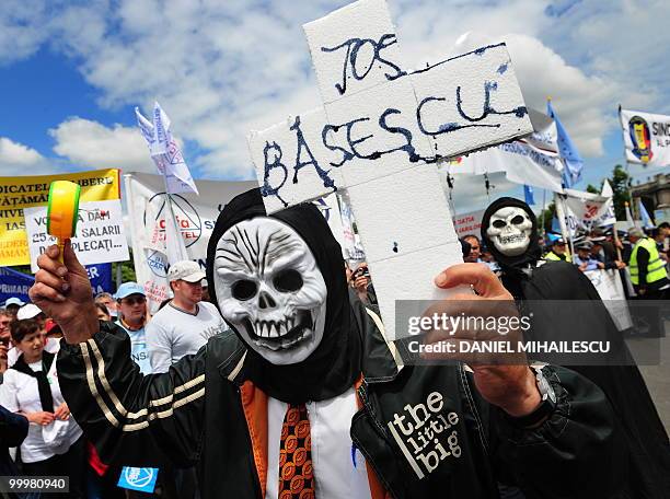 Romanian protester holds a cross reading in Romanian "Down with Basescu" as others shout anti-governmental slogans during a massive protest in the...