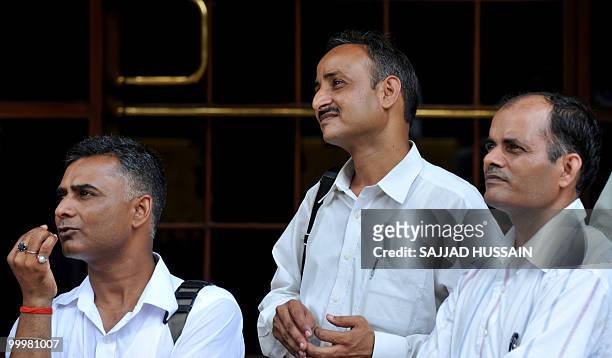 Indian bystanders watch share prices on a digital broadcast board outside The Bombay Stock Exchange in Mumbai on May 19, 2010. Indian shares fell...