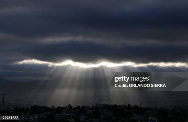 Sun rays appear through the clouds at daybreak in Tegucigalpa, Honduras, on May 17, 2010. AFP PHOTO/Orlando SIERRA