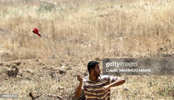 Palestinian man uses a sling shot during a protest on May 19 on the outskirts of Gaza City against the military zone Israel created on Palestinian...