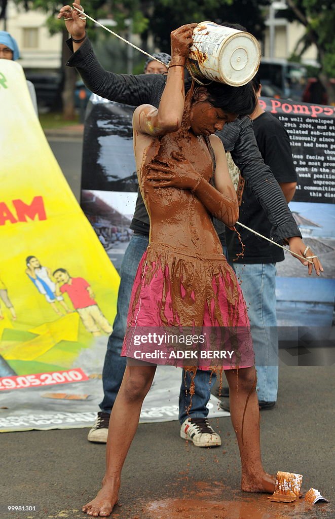 An activist pours mud on himself as he p
